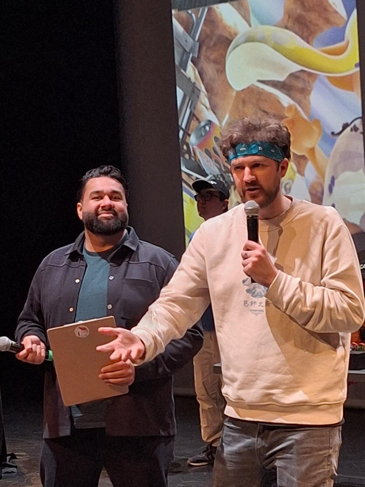 Bowie and Nimmz present with handheld microphones