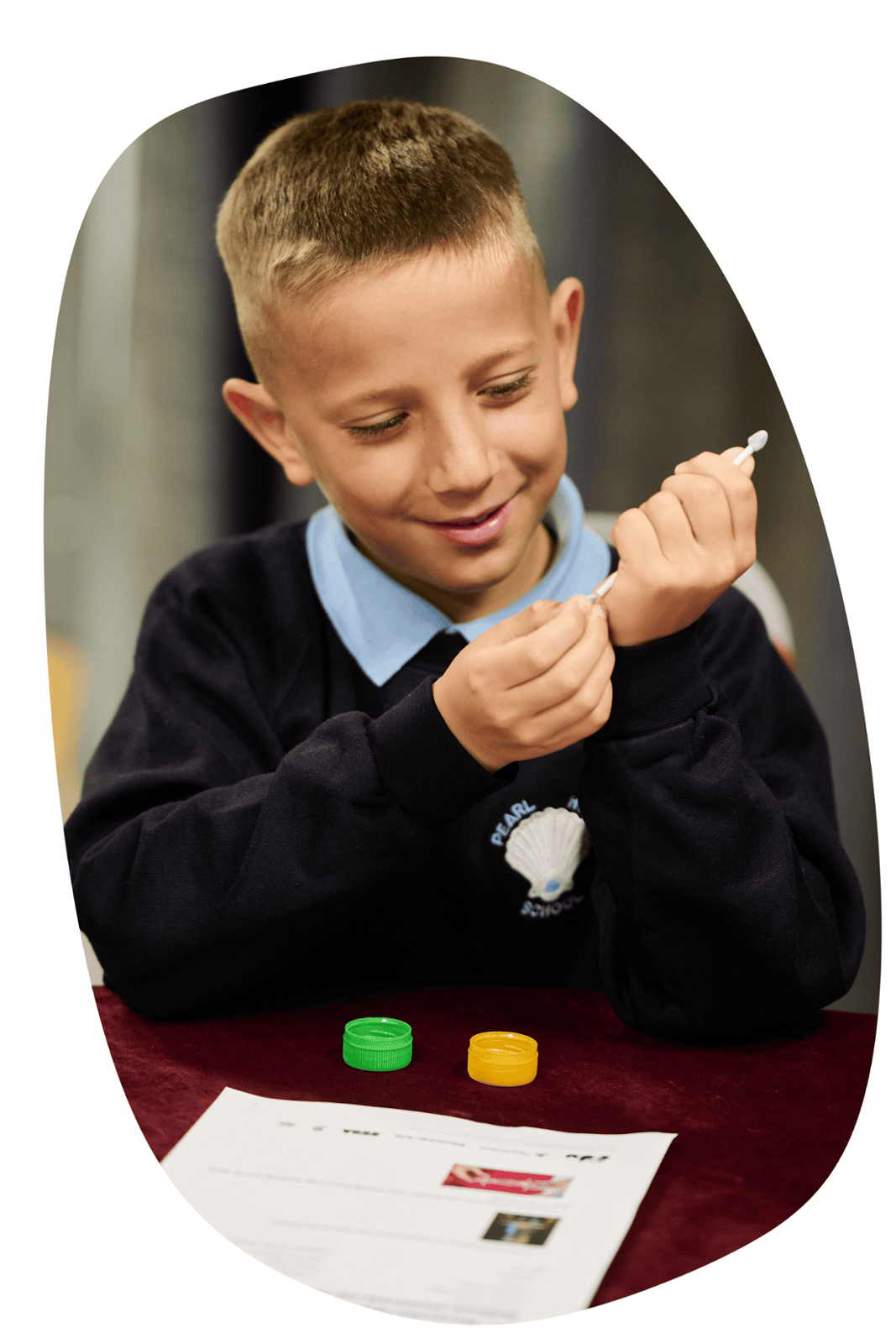 A blonde, primary school aged boy puts two bottle tops on a piece of wood in an F1 workshop by Digital Schoolhouse