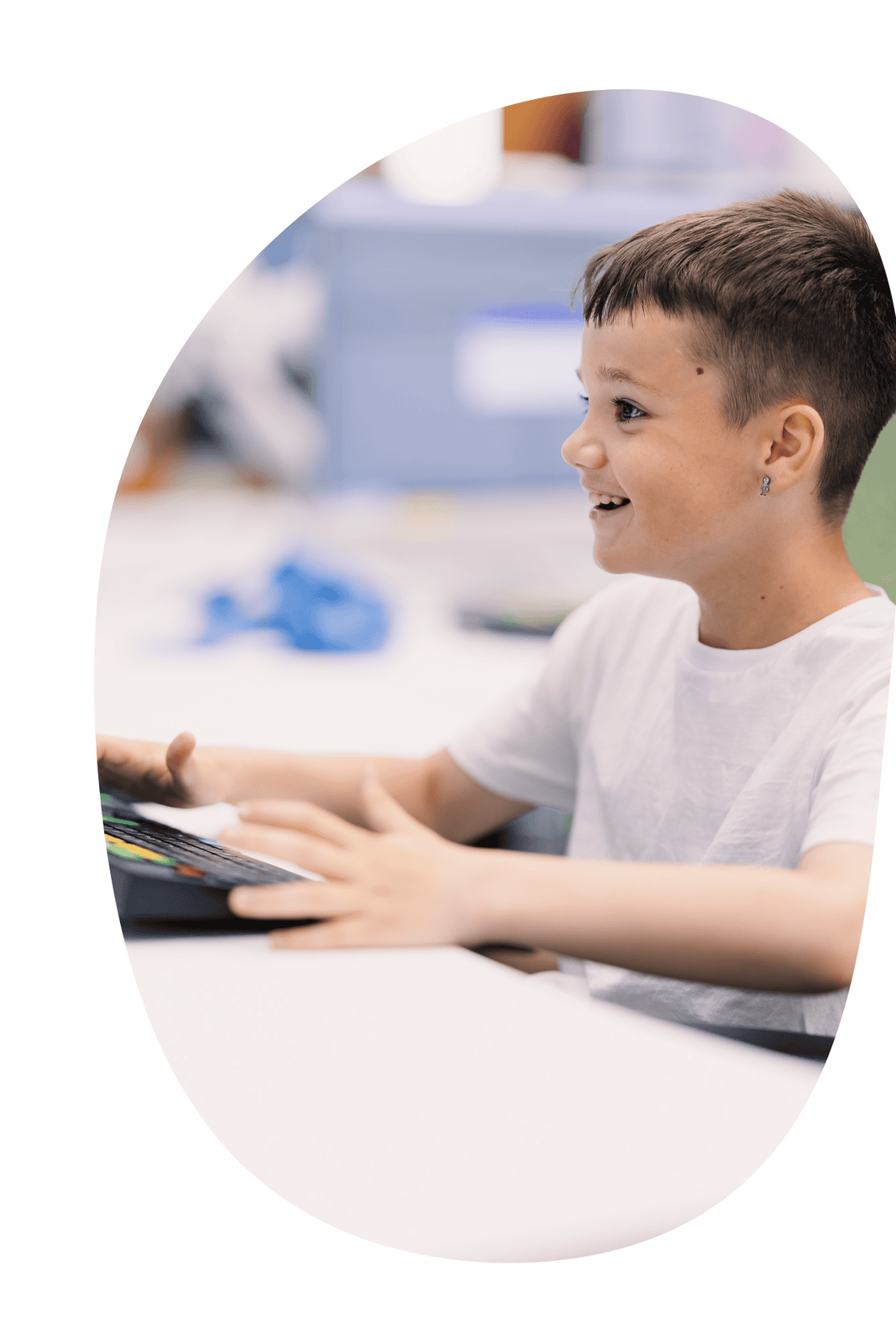 Ayoung boy grins widely as he types on a keyboard in a Digital Schoolhouse workshop
