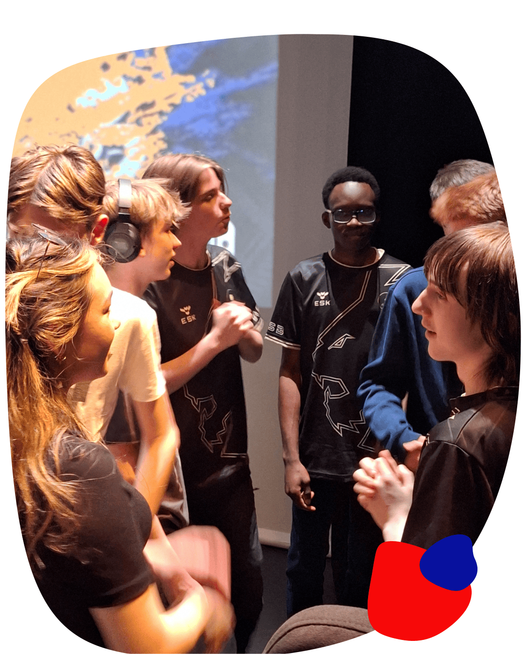 Teenagers who have just played each other at Splatoon 3 esports on Nintendo Switch stand talking  to each other in front of a large video screen